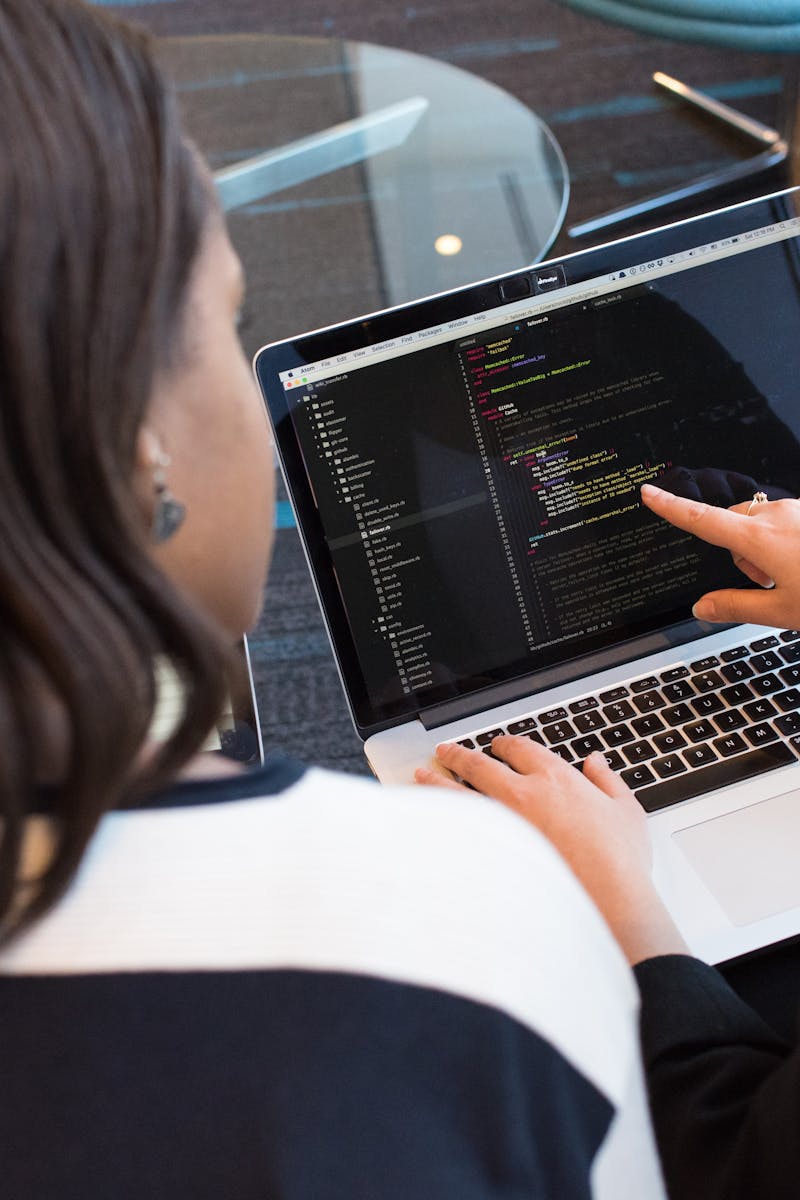 Two women working together on software programming indoors, focusing on code.
