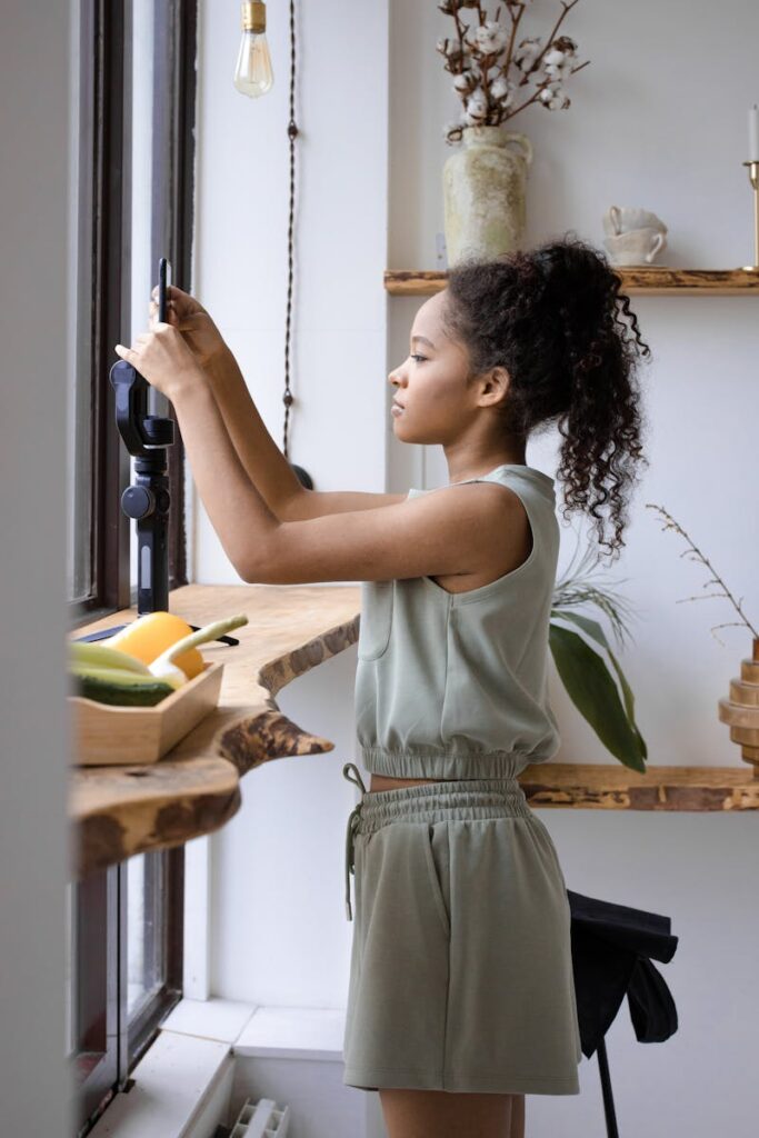 A young woman taking photos with a smartphone indoors, reflecting content creation in a cozy setting.